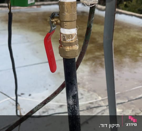 ברז עם ידית אדומה מחובר לצינור שחור
